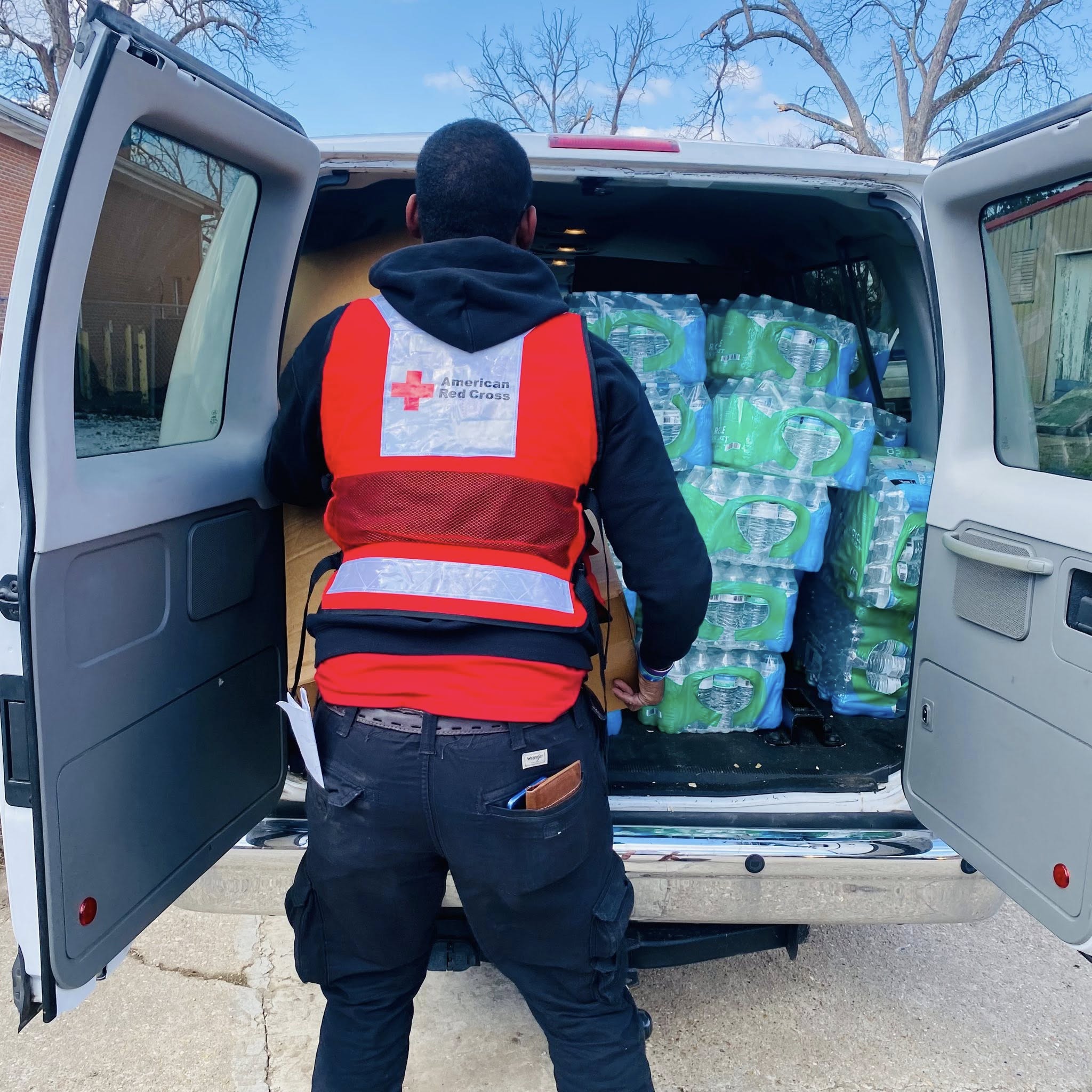 The back of a man wearing an American Red Cross vest.